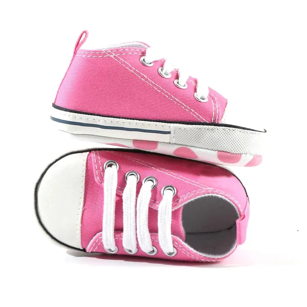 pair of hot pink baby walking shoes for infants with white laces and rubber soles