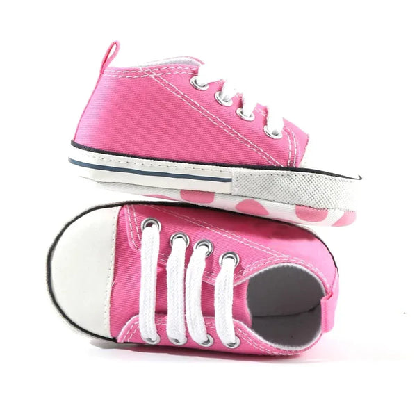 pair of hot pink baby walking shoes for infants with white laces and rubber soles