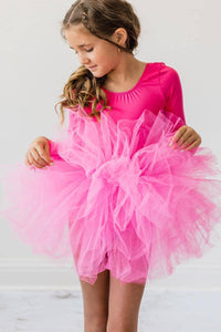young girl wearing hot pink tutu leotard for girls holding the tutu and looking down