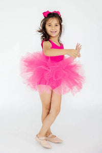 young girl wearing hot pink tutu leotard smiling and posing with arms extended
