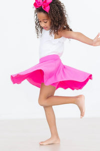little girl wearing hot pink twirl skort for girls spinning barefoot with a matching pink bow