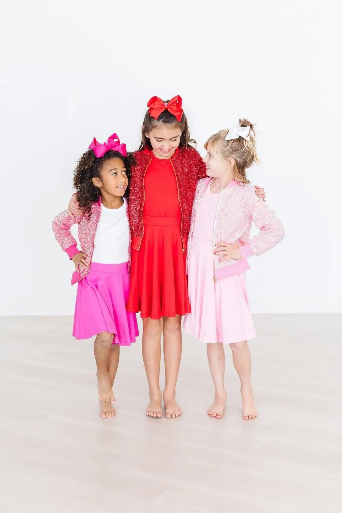 young girl wearing hot pink twirl skort for girls standing barefoot with two other girls in red and pink dresses