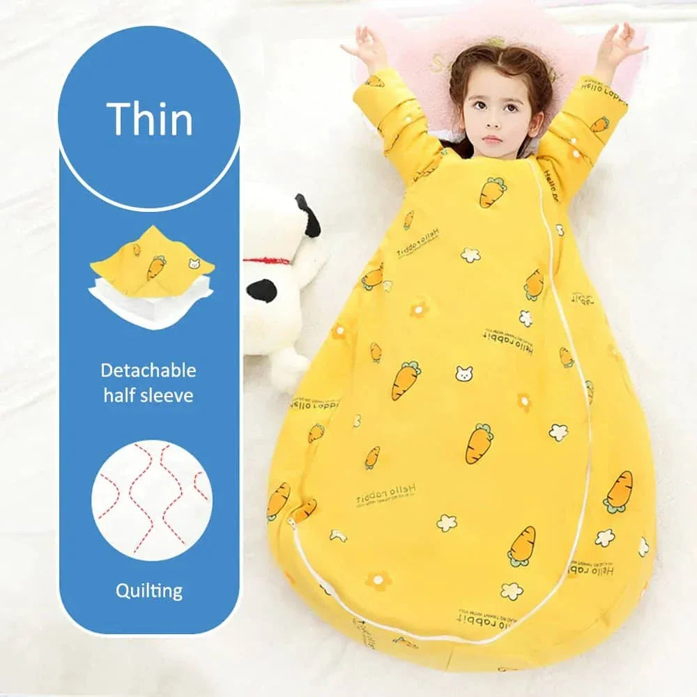 Young girl wearing yellow zippered sleeping bag for kids with carrot prints and detachable sleeves lying down with arms raised