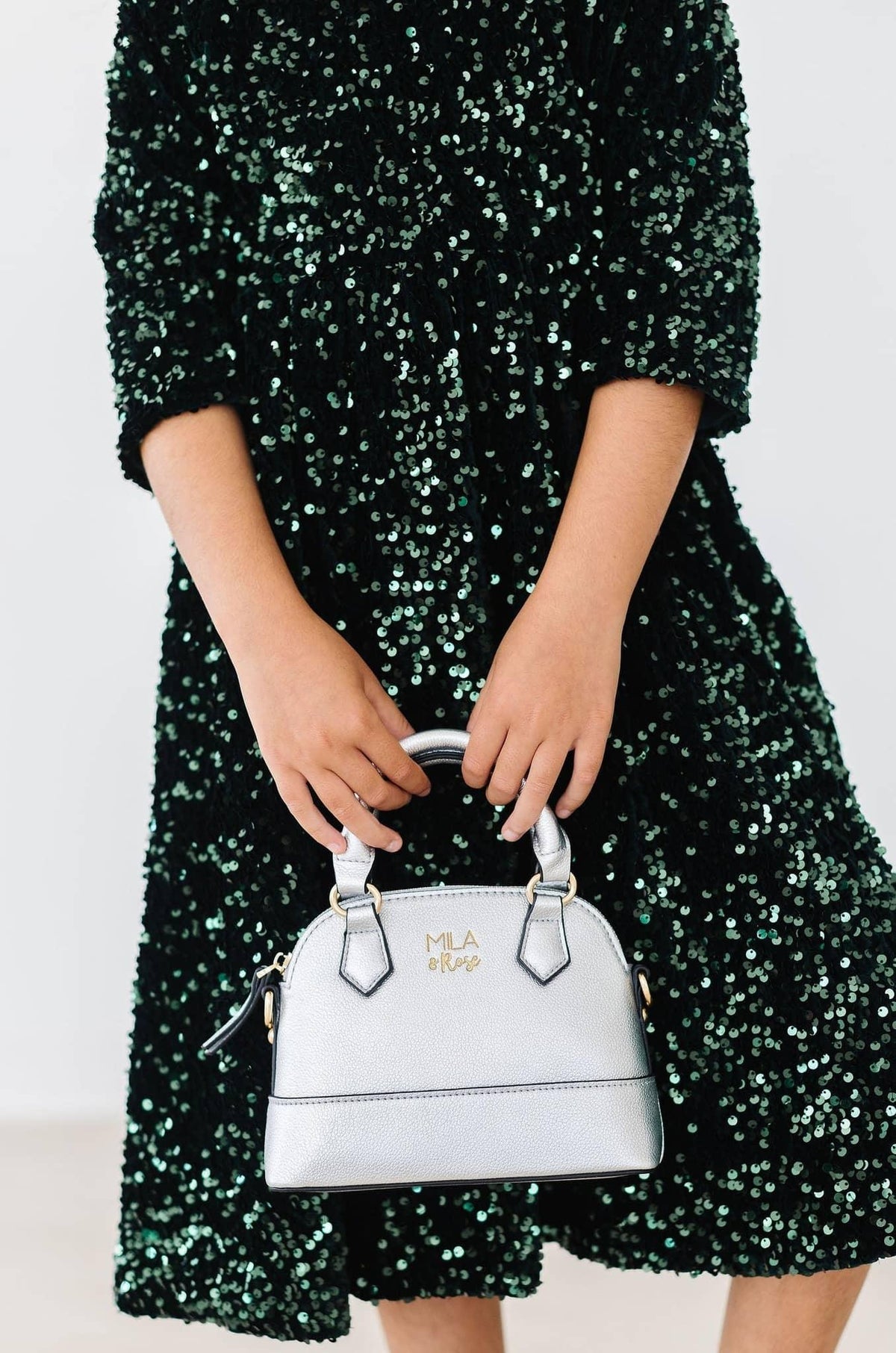 Girls hunter green sequin dress for girls with three-quarter sleeves holding a silver handbag