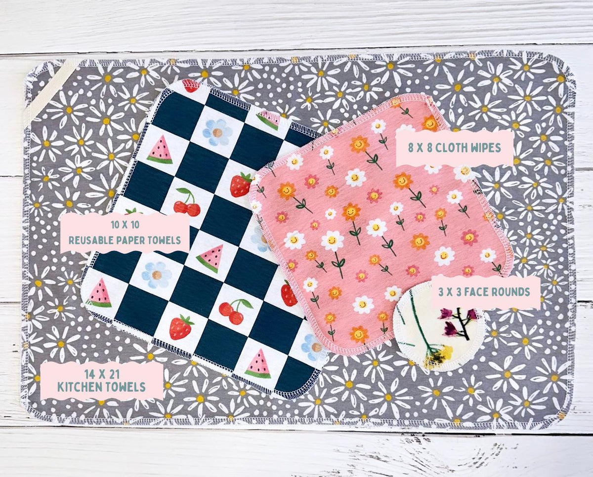 Set of reusable paper towels, cloth wipes, and kitchen towels on a floral patterned mat.