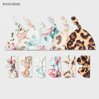Floral baby swaddle blanket set with pink, blue, and brown patterns, includes matching knot hats for newborns