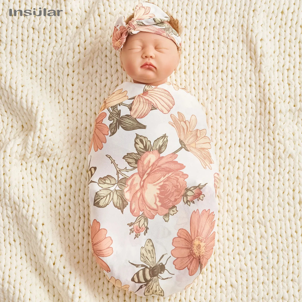 Newborn baby swaddled in white floral baby swaddle blanket set with pink and green flower prints and matching headband