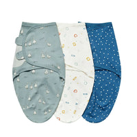 Set of three cotton swaddle bags for babies in blue, white with colorful shapes, and gray with duck prints