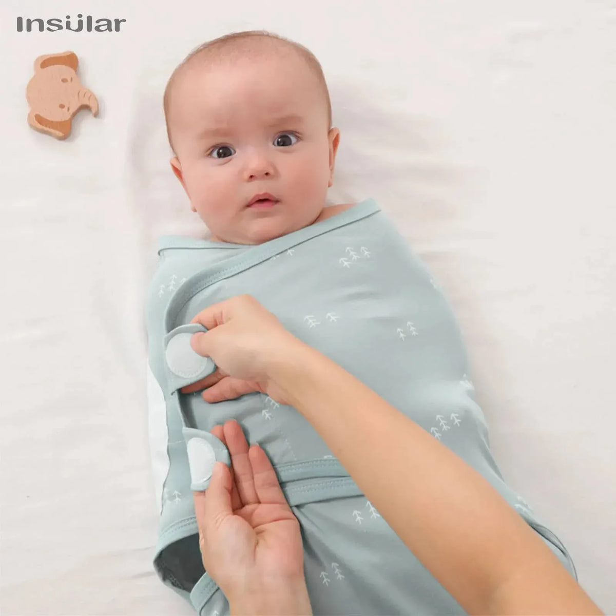 Light blue cotton swaddle bags for babies with white patterns being fastened on a baby