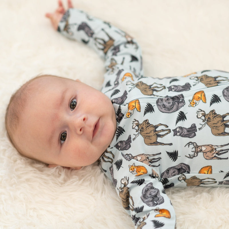 Into the Wild Zipper Footie on a baby with dinosaur print, featuring two-way zipper, silicone grip foot pads, and fold-over cuffs.