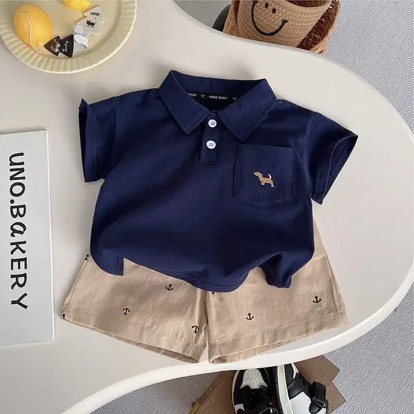 Toddler navy blue polo shirt with beige kids khaki shorts set featuring anchor prints laid flat