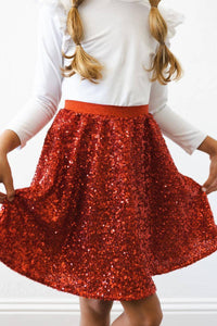 Young girl wearing kids red sequin skort holding the hem and twirling