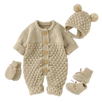 Beige knit romper set for babies with textured pattern, button front, matching hat with pom poms and booties