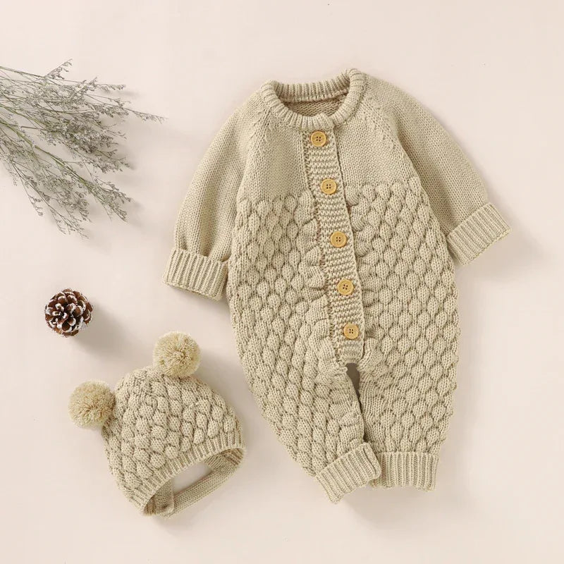 Beige knit romper set for babies with textured knit pattern and matching hat with pom poms