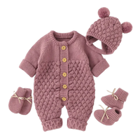 Baby knit romper set in dusty pink with textured pattern, wooden buttons, matching hat with pom poms and booties