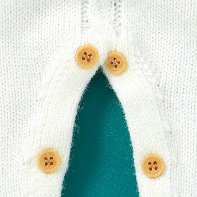 white knit romper for babies with brown wooden buttons and textured knit pattern