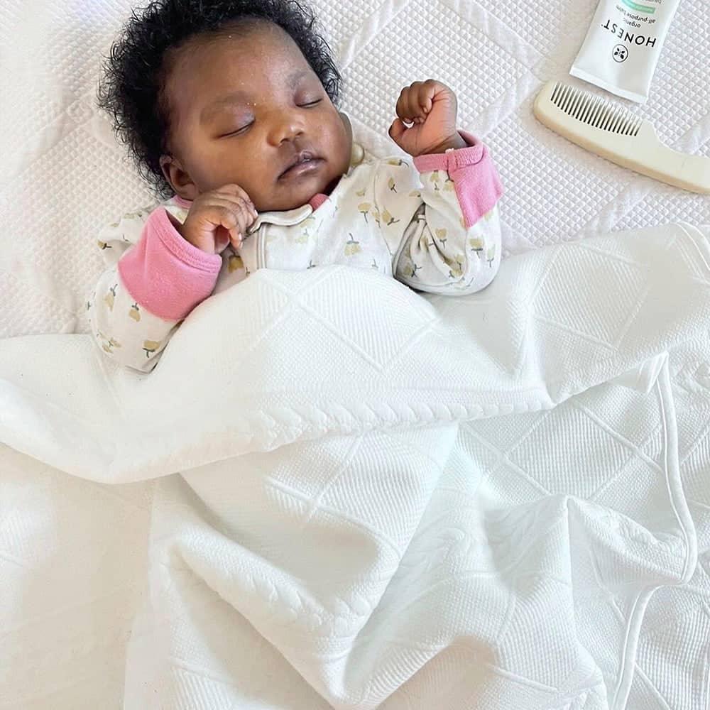 White full size knit throw with geometric detailing, baby asleep under the soft knit throw blanket