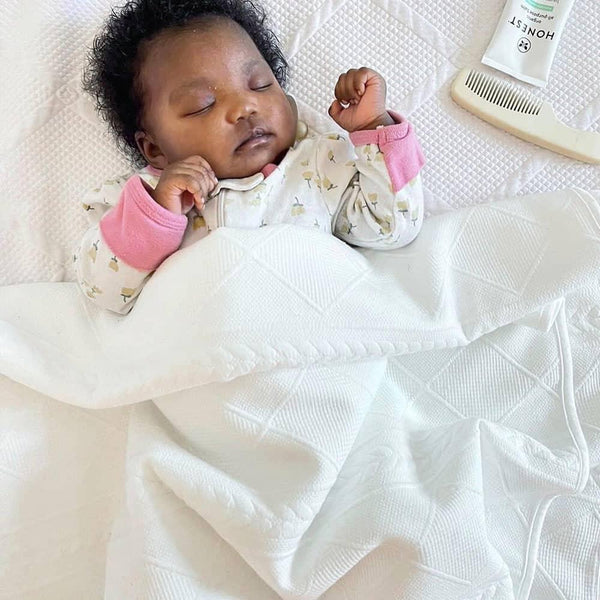 White full size knit throw with geometric detailing, baby asleep under the soft knit throw blanket