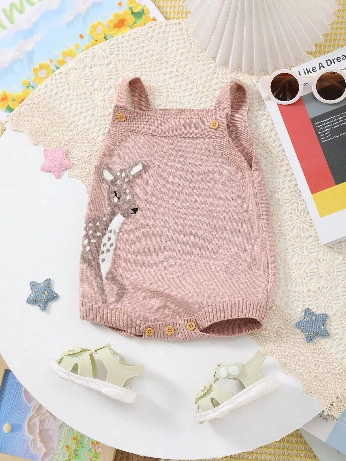 pink knitted baby bubble romper with deer design for infants laid flat with baby sandals
