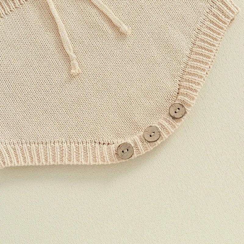beige knitted baby romper for infants with three wooden buttons and drawstring detail