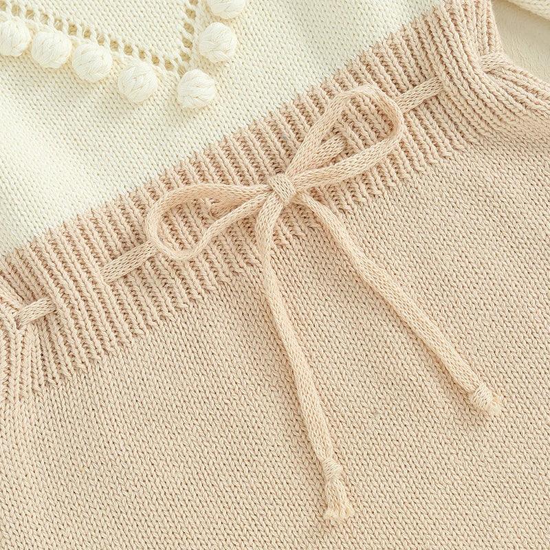 beige knitted baby romper for infants with ribbed waistband and decorative bow detail