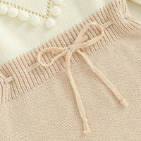 beige knitted baby romper for infants with ribbed waistband and decorative bow detail
