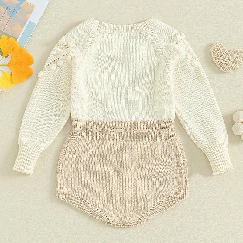 Cream and beige knitted baby romper for infants with pompom details on long sleeves