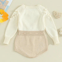 Cream and beige knitted baby romper for infants with pompom details on long sleeves