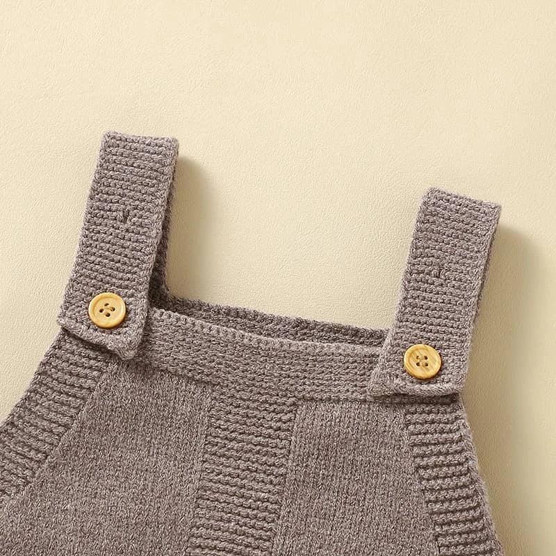 Close-up of gray knitted baby romper overalls straps with wooden buttons for infants