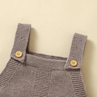 Close-up of gray knitted baby romper overalls straps with wooden buttons for infants