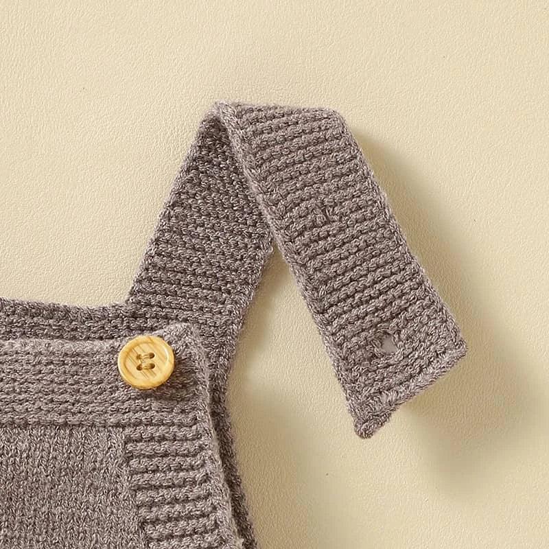 close-up of brown knitted baby romper overalls strap with wooden button for infants