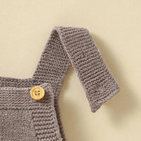 close-up of brown knitted baby romper overalls strap with wooden button for infants