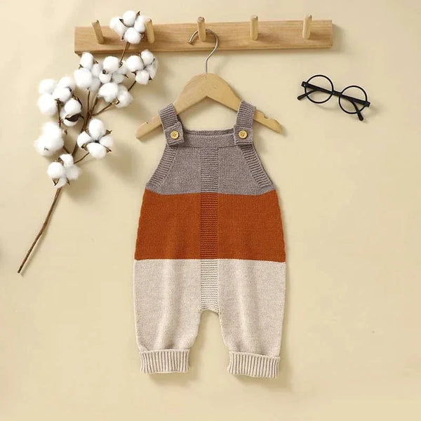 Knitted baby romper overalls in gray, orange, and beige hanging on wooden hanger for infants