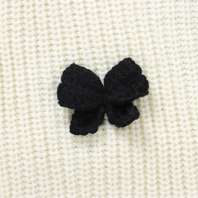 close-up of black bow on white knitted baby romper with bows fabric texture