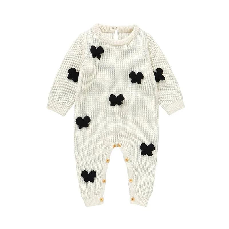cream knitted baby romper with bows in black for infants laid flat with button closure