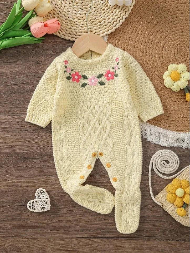Cream knitted baby romper with feet featuring floral embroidery for infants hanging on wooden hanger
