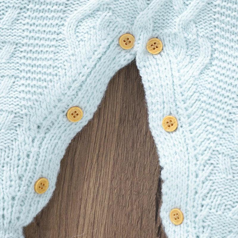 Close-up of light blue knitted baby romper with feet showing wooden buttons on size newborn to 3 months