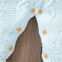 Close-up of light blue knitted baby romper with feet showing wooden buttons on size newborn to 3 months