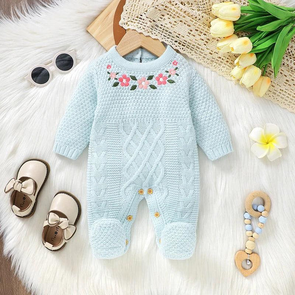 light blue knitted baby romper with feet featuring floral embroidery for infants displayed on a white fur surface