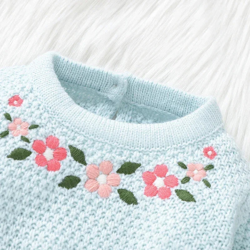 Light blue knitted baby romper with feet featuring pink and coral flower embroidery on chest for infants