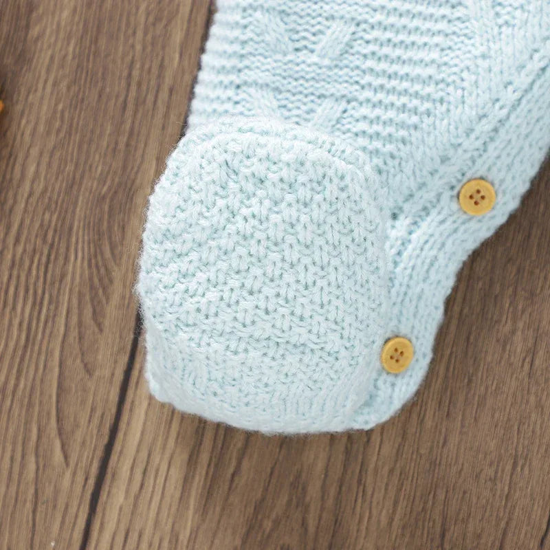 Light blue knitted baby romper with feet for infants showing textured knit and wooden buttons