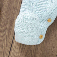 Light blue knitted baby romper with feet for infants showing textured knit and wooden buttons