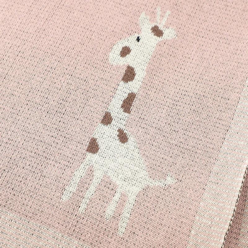 Pink knitted giraffe baby blanket for infants featuring a white and brown giraffe design