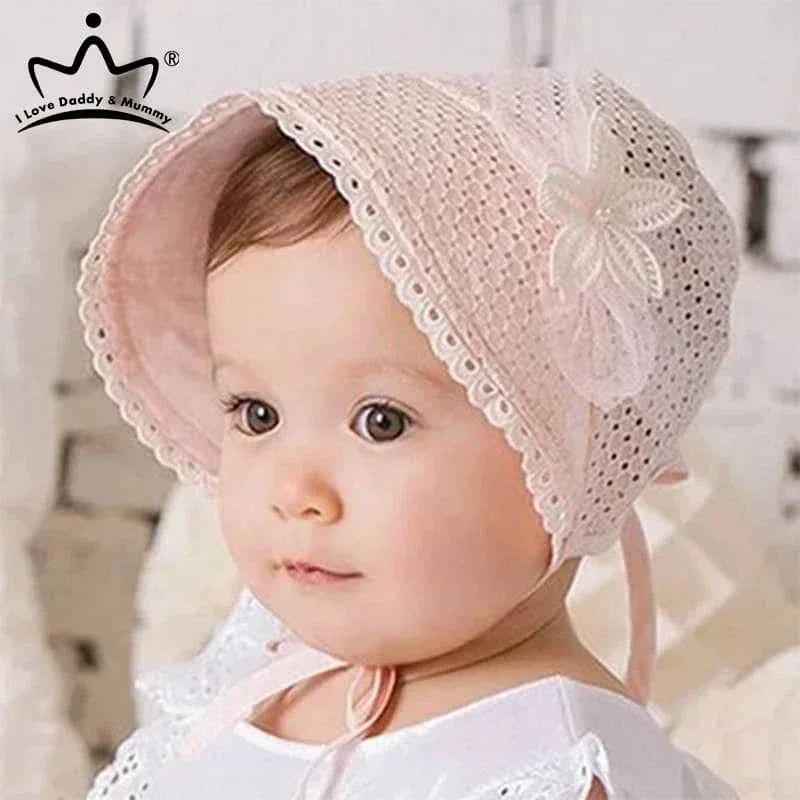 baby wearing pink lace baby bonnet with flower decoration looking sideways