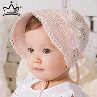 baby wearing pink lace baby bonnet with flower decoration looking sideways