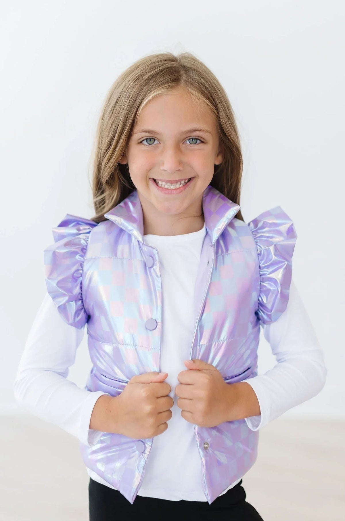 Lavender checker puffer vest for girls with ruffled shoulder detail, worn by smiling child