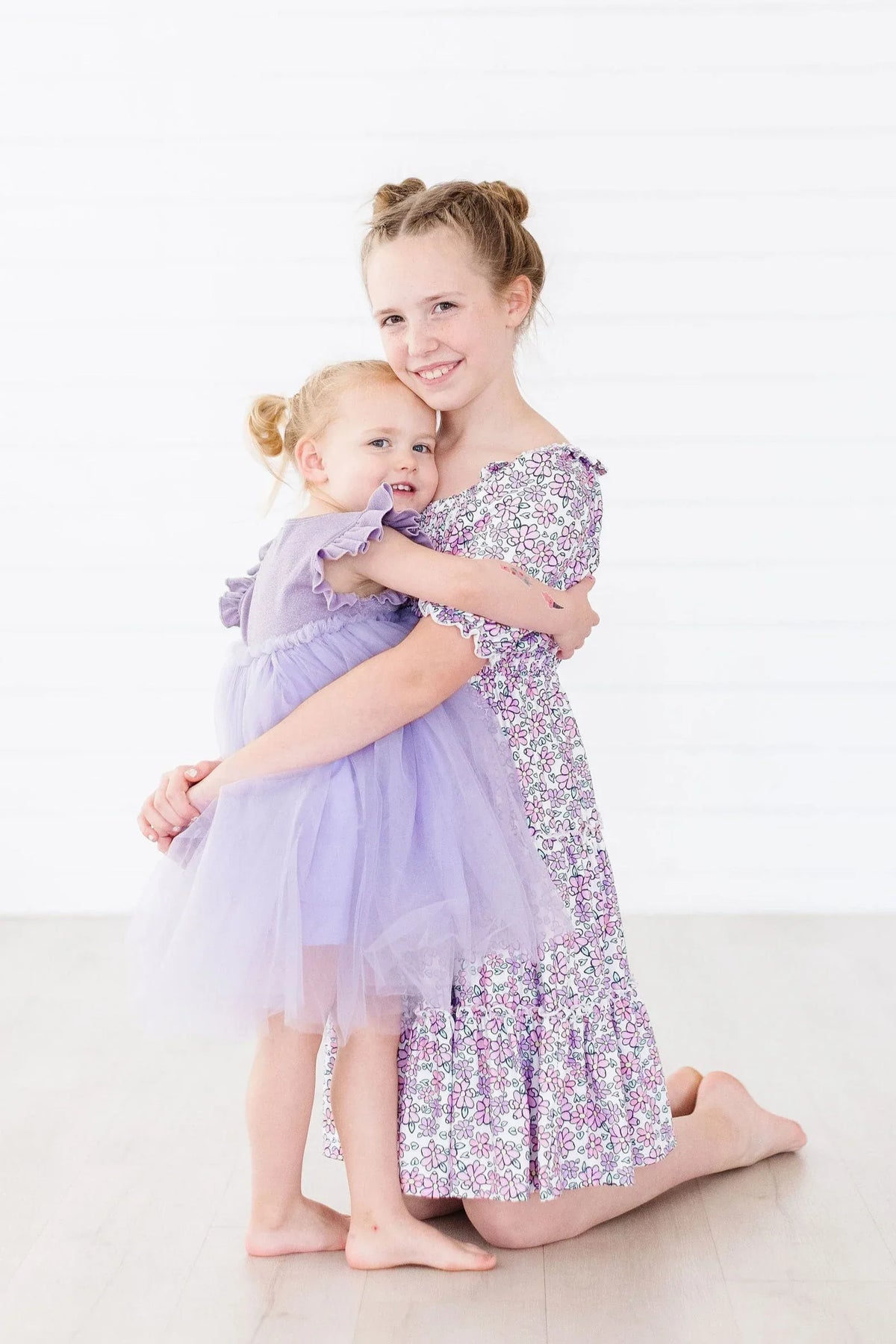 Girls lavender floral smocked dress for girls with ruffle sleeves worn by two children