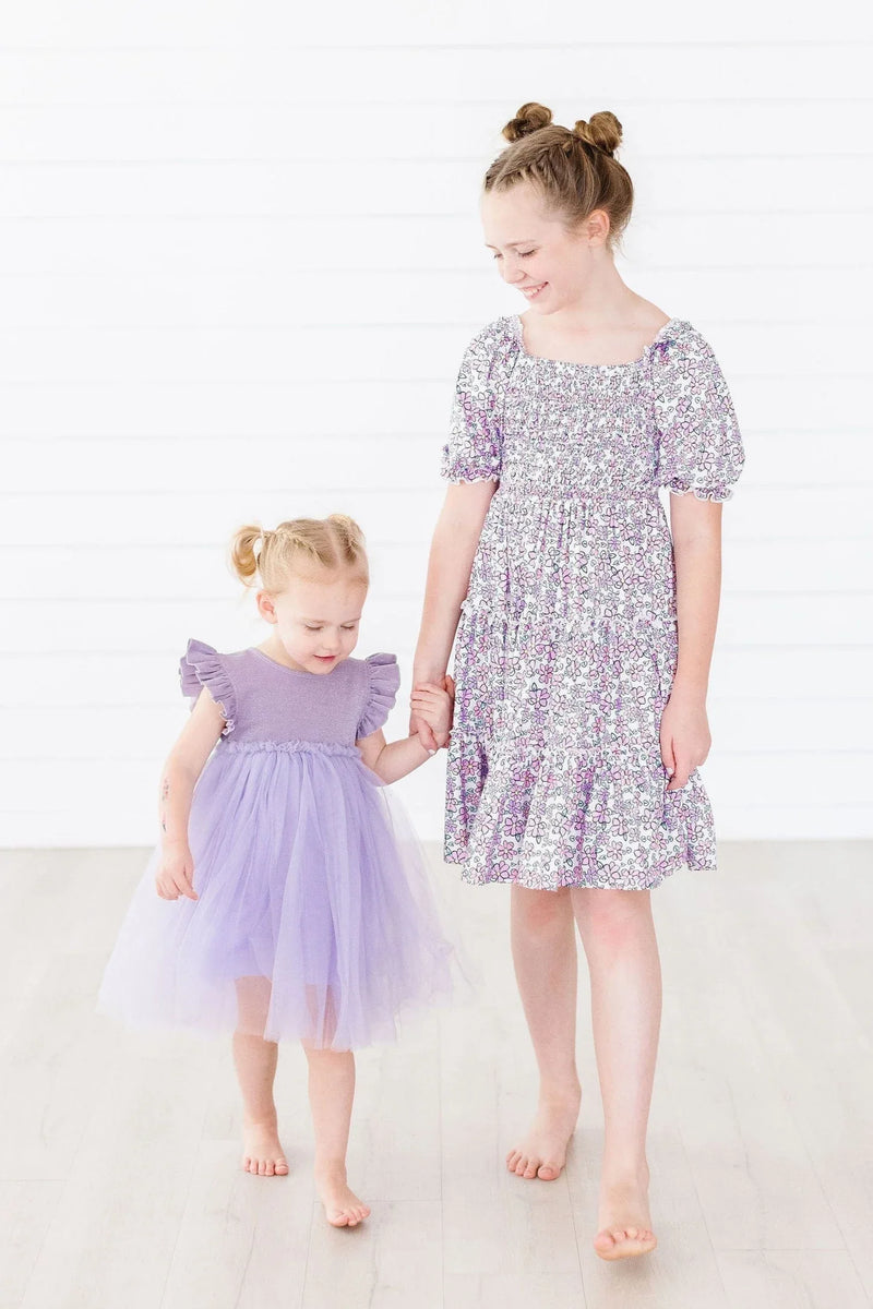 Lavender floral smocked dress for girls with puff sleeves and ruffle hem worn by older girl