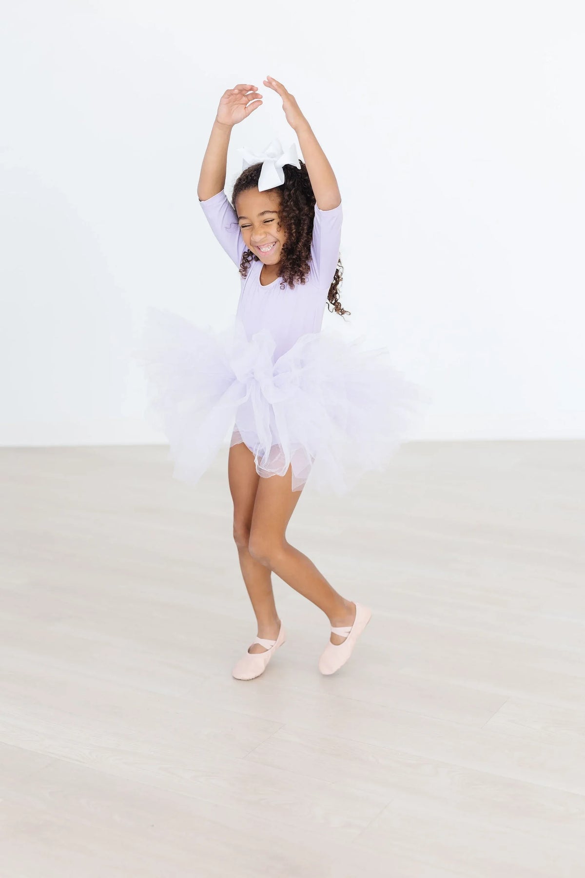 Lavender tutu leotard for toddlers with sleeves and fluffy tulle skirt worn by a smiling girl