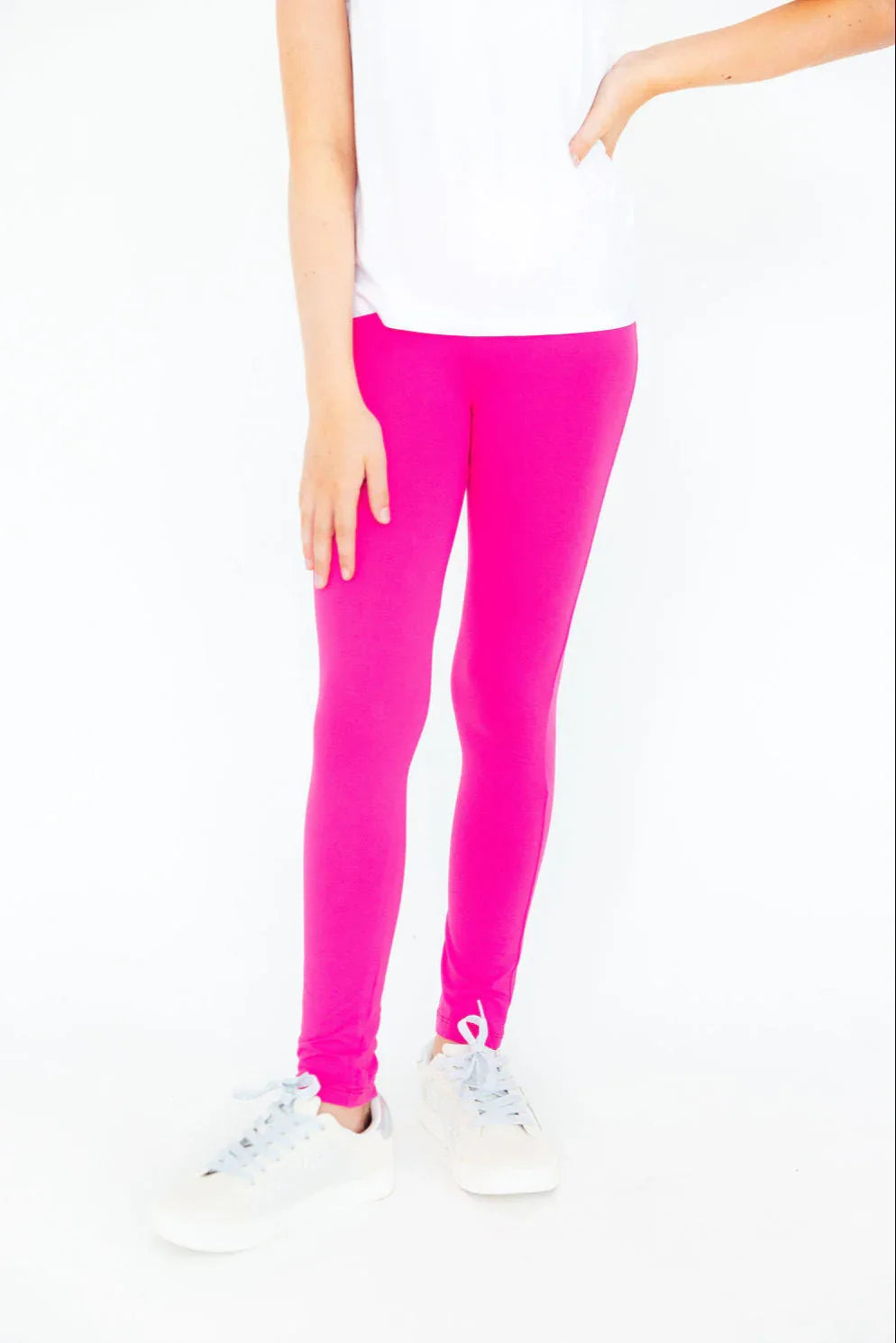 child wearing bright pink Mila & Rose leggings standing with one hand on hip and white sneakers